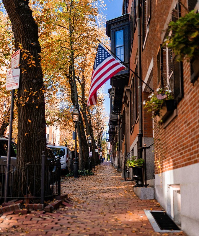 A street with brick buildings, an American flag and fall foliage