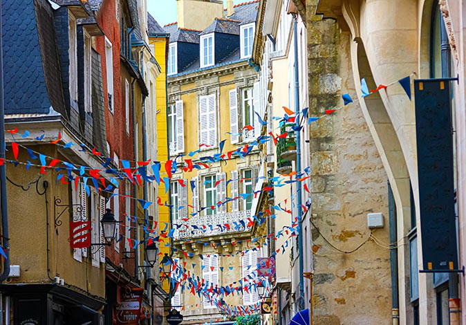 A narrow street with colorful houses decorated with small flags