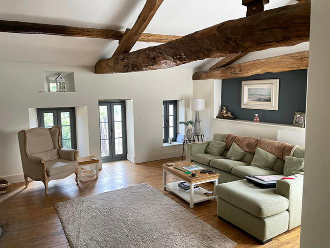 A lliving room with white walls, wooden beams and light furniture