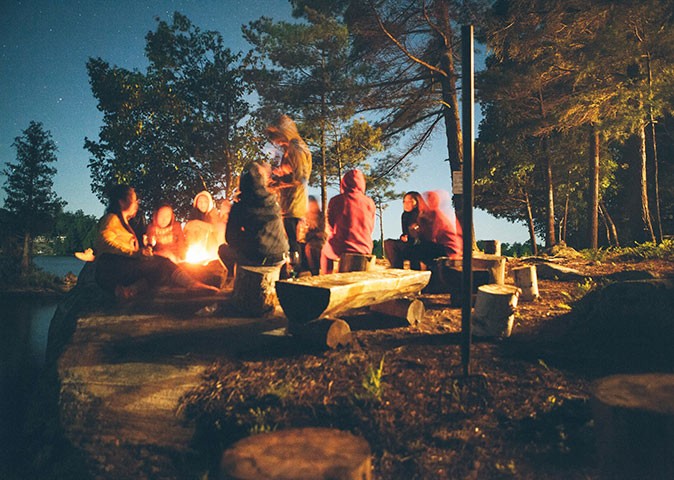 people sitting around a campfire in a forest