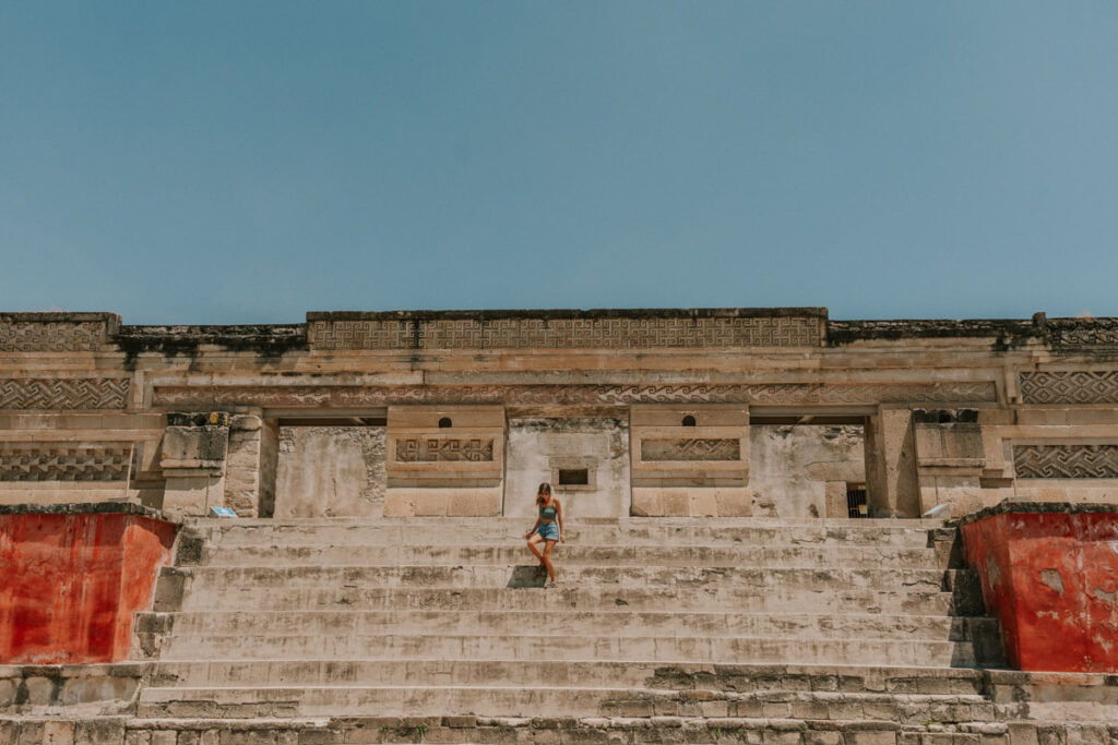 Woman walking down the steps of an ancient Zapotec building at Mitla on a one week Oaxaca City itinerary