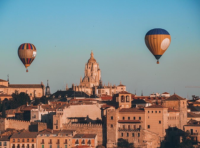 2 hot air balloons floating above historic buildings