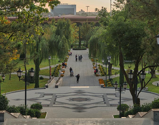 A square and path with people, lined with trees on both sides