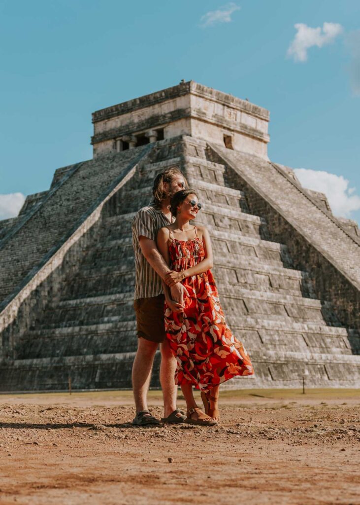 Couple embracing in front of El Castillo ruins at Chichen Itza, one the best places to see on this Valladolid itinerary