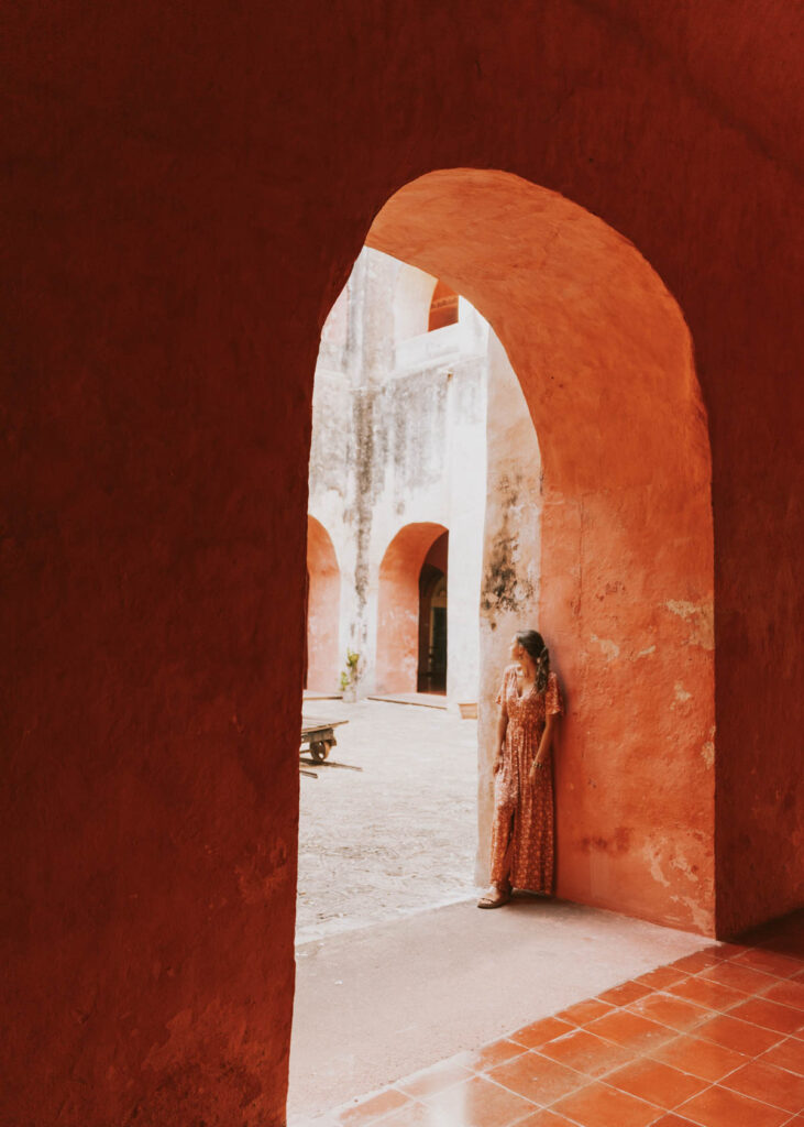 Woman leaning against pink wall in Convento de San Bernardino de Siena, a favorite stop on this Valladolid Mexico itinerary
