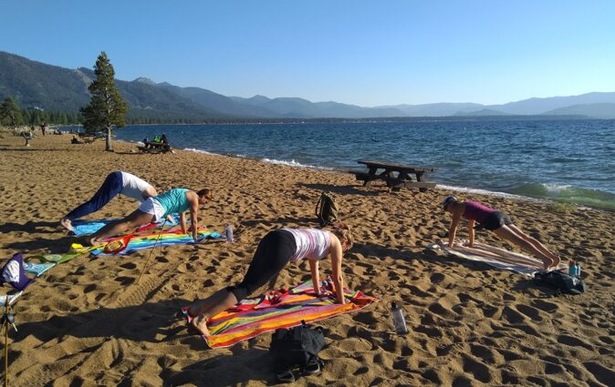 4 woman doing yoga on a sandy beach