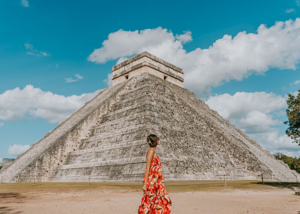 Woman in dress standing in front of El Castillo temple at Chichen Itza, a popular Cancun day trip destination